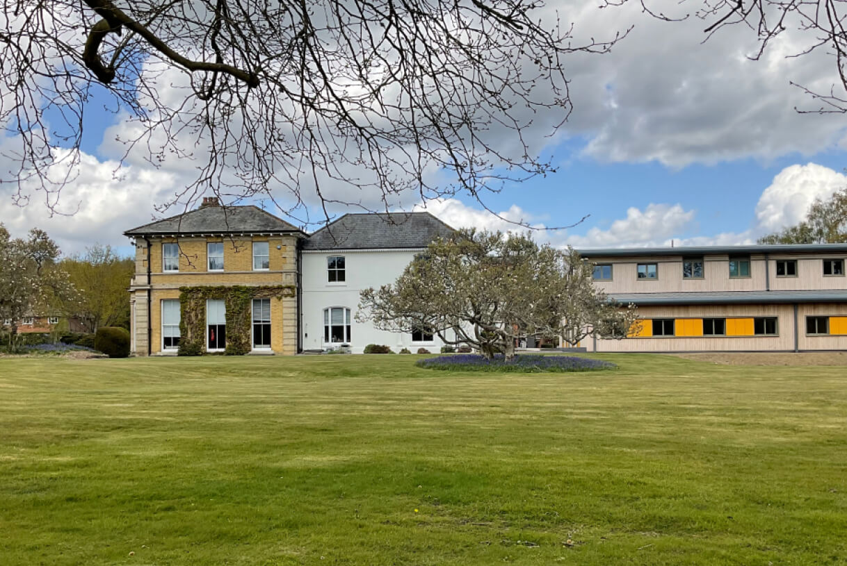 An old building with a lawn in front and a modern laboratory building on the right hand side.