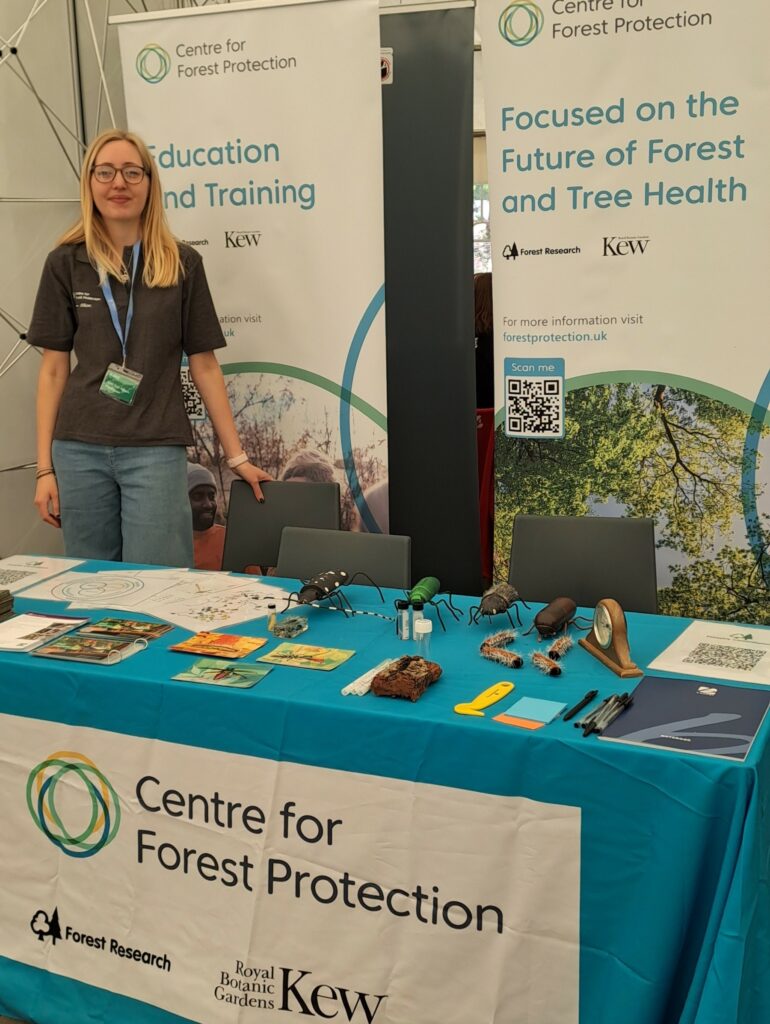 A woman standing behind a table with a CFP branded cloth and careers leaflets on it.